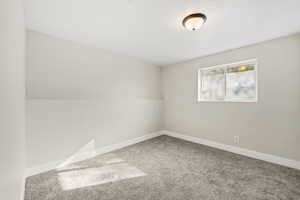 Spare room featuring carpet flooring and baseboards