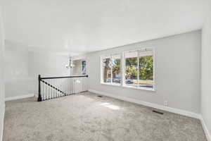 Carpeted empty room featuring a chandelier and a textured ceiling