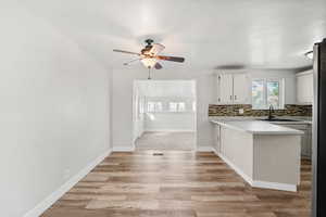 Kitchen with a peninsula, light countertops, backsplash, light wood finished floors, and a ceiling fan