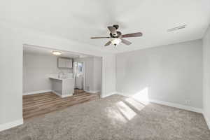 Unfurnished living room with light carpet, washer / clothes dryer, and a ceiling fan