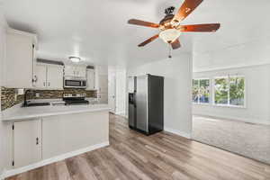Kitchen featuring appliances with stainless steel finishes, light countertops, open floor plan, decorative backsplash, and a peninsula