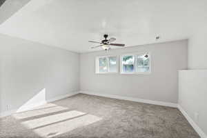 Empty room featuring light colored carpet, a textured ceiling, and a ceiling fan