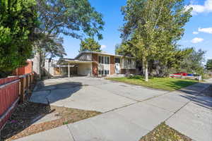 Bi-level home featuring an attached carport, driveway, and brick siding