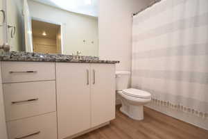 Full bath with light wood-style floors, vanity, and curtained shower