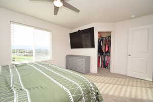 Bedroom with carpet, a walk in closet, and ceiling fan