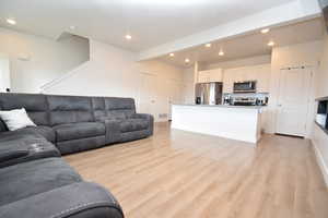 Living area featuring recessed lighting, light wood-style flooring, and beamed ceiling