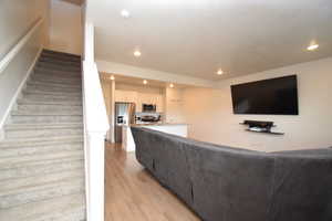 Living area with light wood-type flooring, stairs, and recessed lighting