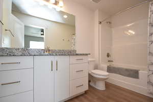 Bathroom featuring vanity, light wood-style flooring, shower / tub combo with curtain, and recessed lighting