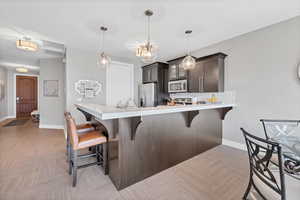 Kitchen with tasteful backsplash, a breakfast bar, dark brown cabinets, a peninsula, and appliances with stainless steel finishes
