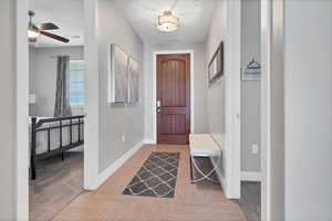 Entrance foyer featuring a ceiling fan and light carpet