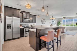 Kitchen featuring stainless steel appliances, light countertops, a breakfast bar, glass insert cabinets, and decorative backsplash