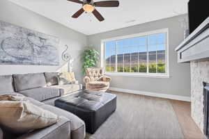 Living room featuring a stone fireplace and ceiling fan