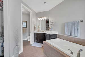 Full bath with a garden tub, vanity, and a closet