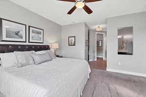 Bedroom with connected bathroom, ceiling fan, and wood finished floors