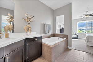 Full bath with plenty of natural light, a garden tub, vanity, and a ceiling fan