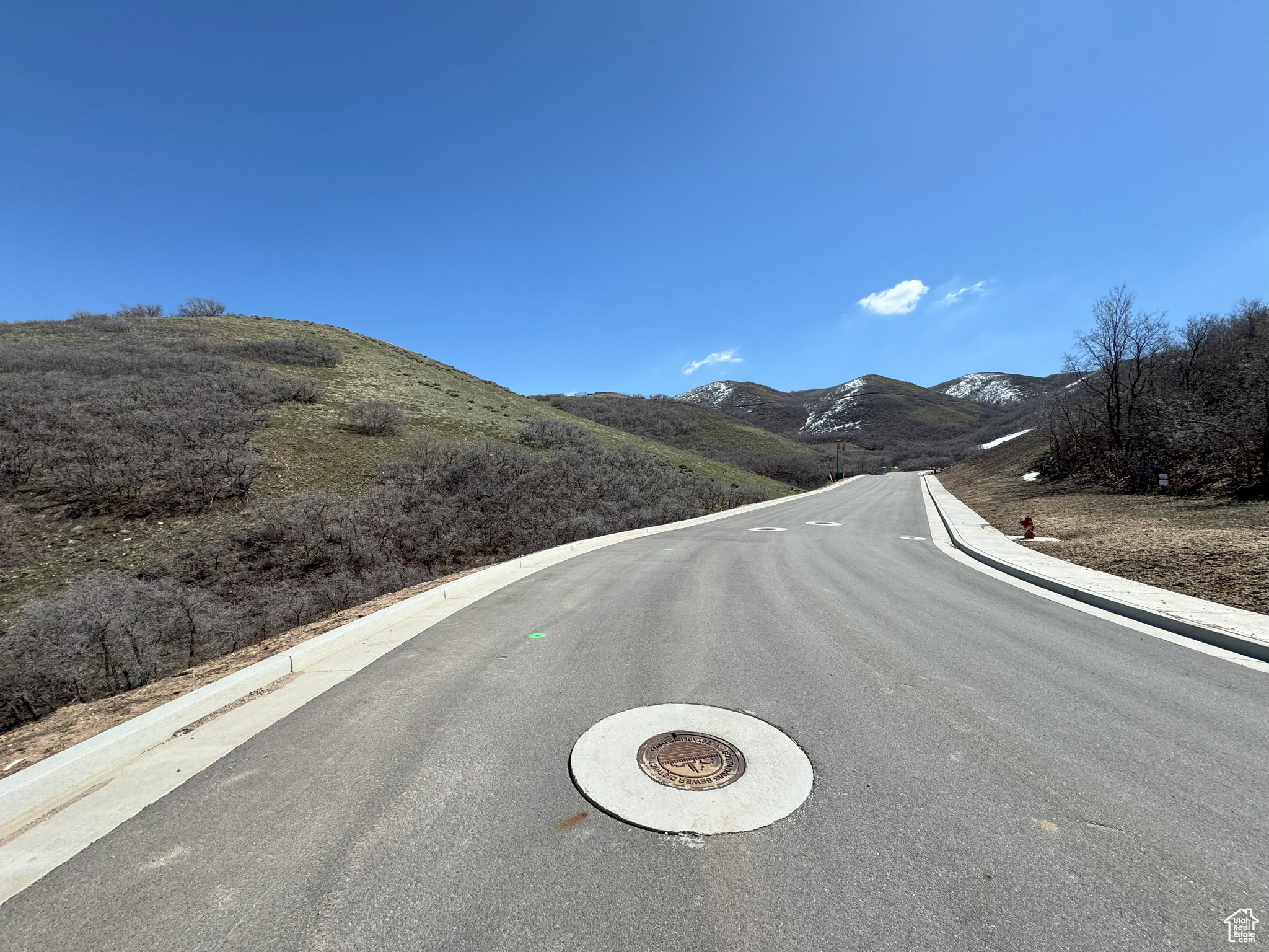 View of asphalt road featuring curbs and a mountain view