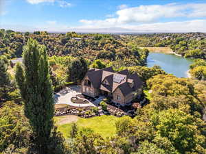 Aerial view of property and surrounding area with a large body of water and a forest