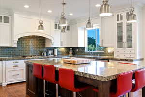 Kitchen featuring glass insert cabinets, a kitchen bar, tasteful backsplash, a kitchen island, and recessed lighting