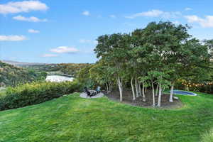 View of green lawn with a patio area and a water view