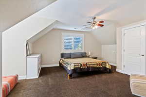 Bedroom featuring dark carpet, vaulted ceiling, and ceiling fan