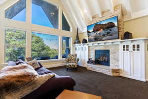 Carpeted living room featuring high vaulted ceiling, a brick fireplace, and beamed ceiling