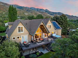 Back of property featuring an outdoor living space, a shingled roof, stucco siding, a deck with mountain view, and a hot tub