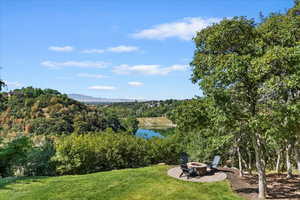 View of home's community with an outdoor fire pit, a water and mountain view, a patio, and a yard