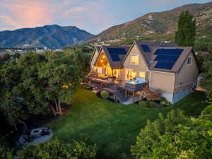 Back of house at dusk with stairs, a yard, a fire pit, stucco siding, and solar panels