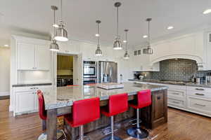 Kitchen featuring appliances with stainless steel finishes, a kitchen breakfast bar, light wood finished floors, recessed lighting, and decorative backsplash
