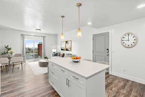 Kitchen featuring white cabinets, open floor plan, light countertops, dark wood finished floors, and hanging light fixtures