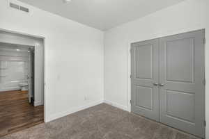 Unfurnished bedroom with dark carpet and a closet