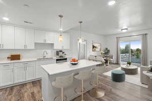 Kitchen with pendant lighting, white cabinetry, a kitchen bar, dark wood-style floors, and open floor plan