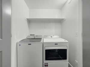 Washroom featuring washing machine and clothes dryer and baseboards