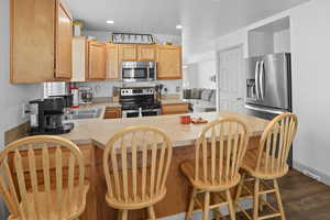 Kitchen with appliances with stainless steel finishes, light countertops, recessed lighting, dark wood-style floors, and a peninsula