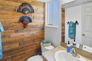Half bathroom featuring wooden walls and vanity