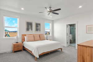 Bedroom with light colored carpet, ceiling fan, recessed lighting, and ensuite bathroom