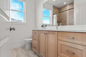 Full bathroom with vanity, a tile shower, and light wood-type flooring