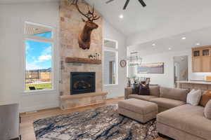 Living room featuring high vaulted ceiling, a fireplace, light wood finished floors, recessed lighting, and a ceiling fan