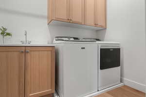 Laundry room featuring washer and clothes dryer, light wood-type flooring, and cabinet space