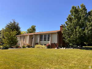 Bi-level home with a chimney and a front lawn