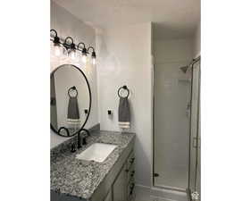 Full bathroom with vanity, a stall shower, and a textured ceiling