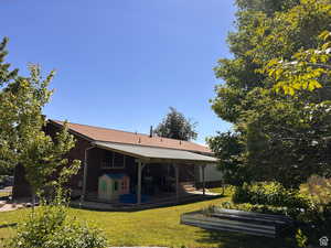 Rear view of house featuring a lawn, a patio area, and a vegetable garden