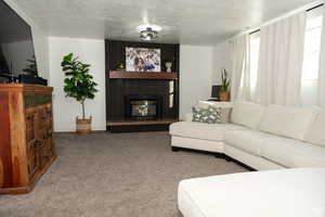Carpeted living area featuring a brick fireplace and a textured ceiling