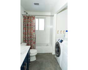 Bathroom featuring shower / tub combo, vanity, washing machine and dryer, dark tile patterned floors, and a textured ceiling