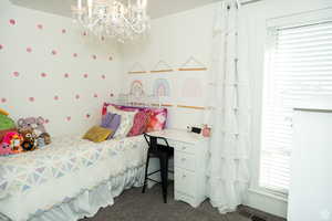 Bedroom with dark carpet and a chandelier