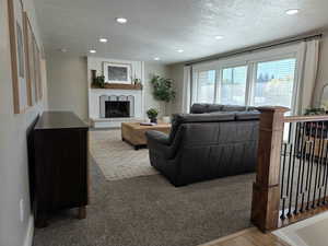 Living room featuring a textured ceiling, a fireplace, recessed lighting, and carpet