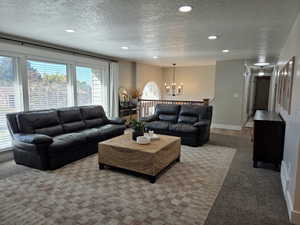 Living area with a textured ceiling, a chandelier, carpet, and recessed lighting