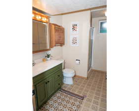 Bathroom with a textured ceiling, vanity, and a stall shower