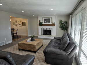 Living area featuring a fireplace, a textured ceiling, carpet, and recessed lighting