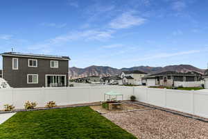 Fenced backyard featuring a mountain view. This really is so nice and open!  Fun sandbox area!
